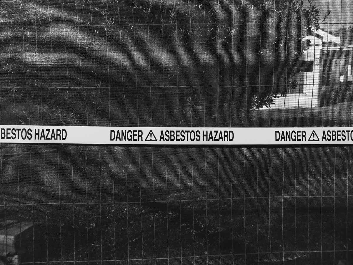 Danger asbestos hazard tape across a site fence